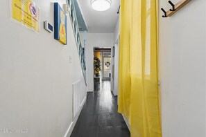 A hallway with a yellow curtain, a sign indicating quiet hours, and a door leading to a room with a view.