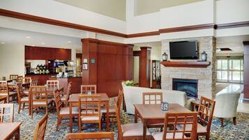A hotel lobby with a bar area, seating arrangements, and a fireplace.