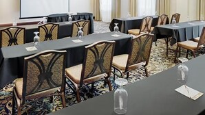 A conference room with tables, chairs, a projector screen, and a carpeted floor.