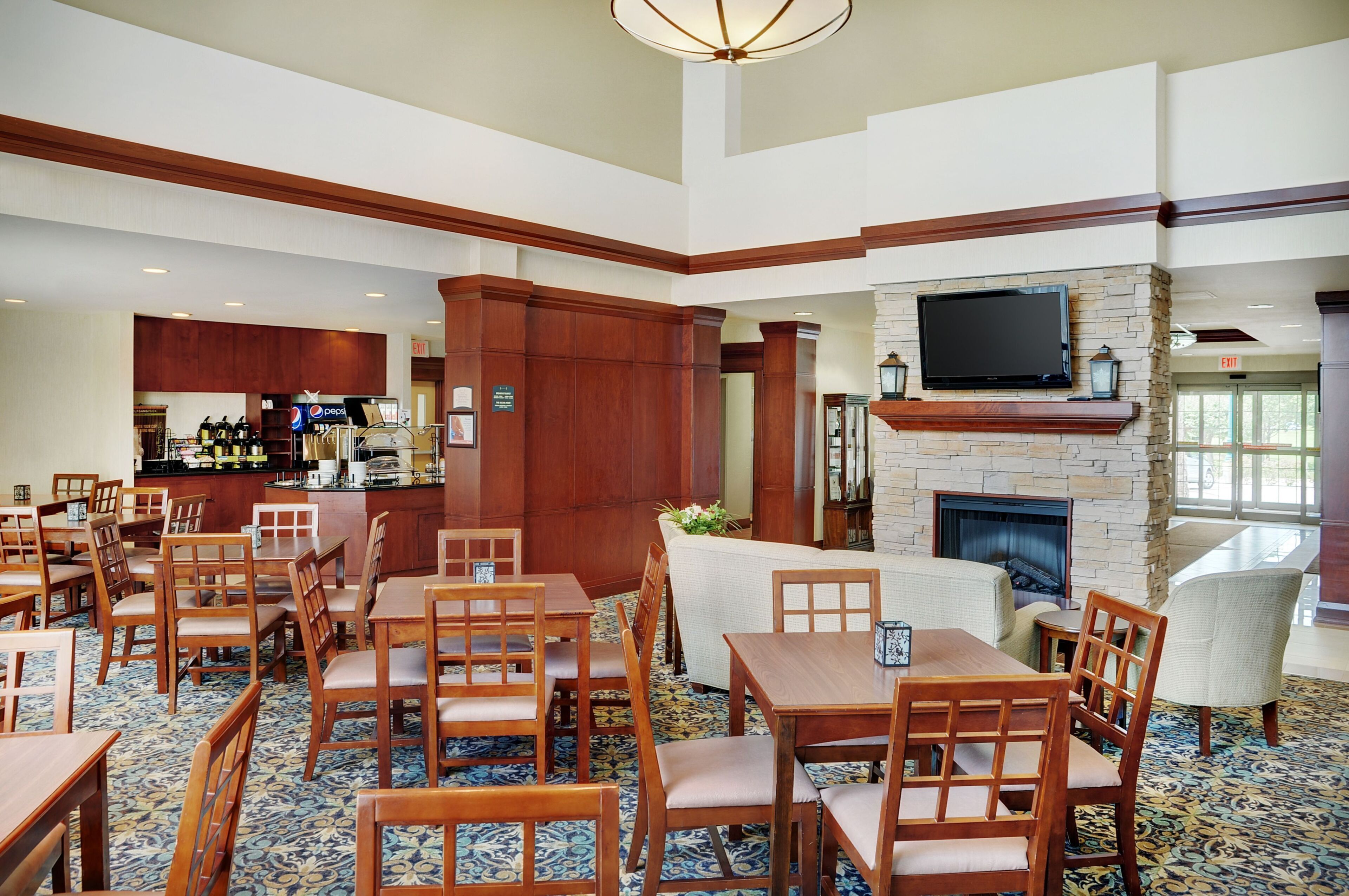 A hotel lobby with a bar area, seating arrangements, and a fireplace.