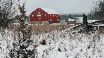 A red barn with a sign that reads 'Baker Creek Children's Farm' in a snowy field.