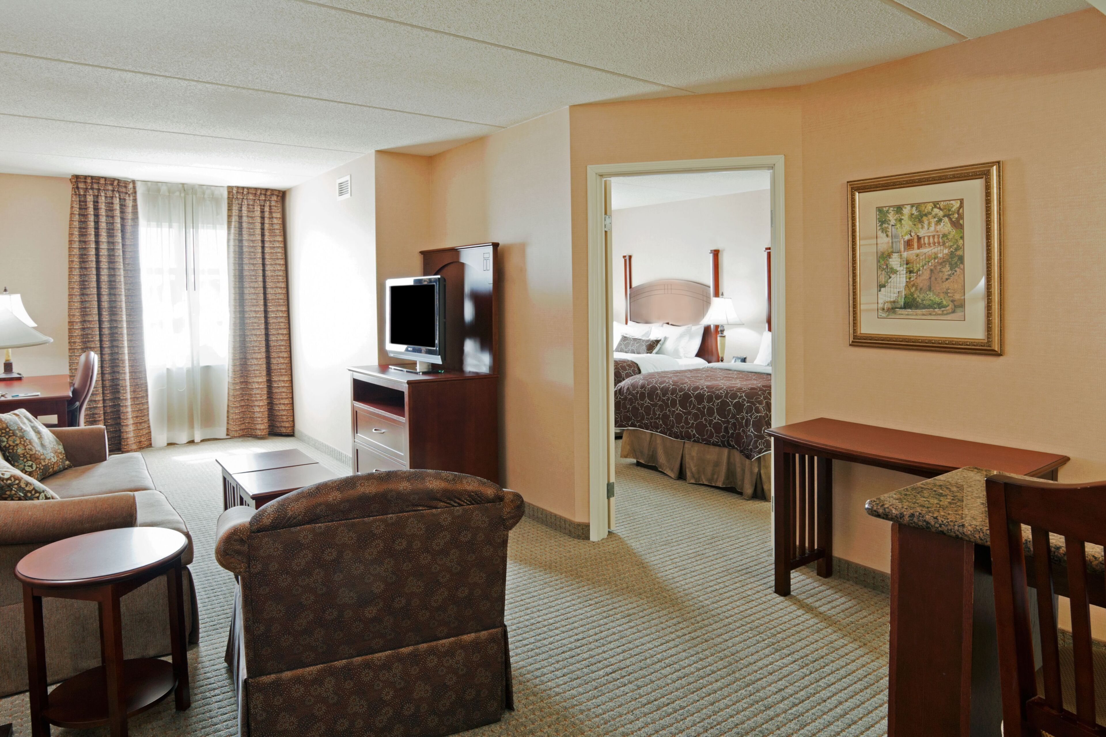 Een hotelkamer met een bed, een bureau met een televisie, een bank, een stoel en een kleine tafel.