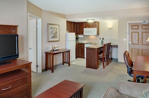 A compact living space with a kitchenette, a dining area with a table and chairs, and a television on a stand.