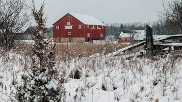 A red barn with a sign that reads 'Baker Creek Children's Farm' in a snowy field.