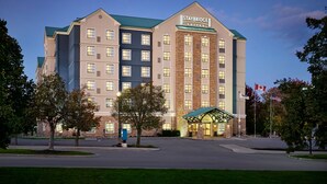 Ein Staybridge Suites Hotel mit markantem Eingangsbereich, mehreren Etagen und einer Kombination aus Backstein- und moderner Fassade.