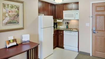 A compact kitchen with wooden cabinets, a white refrigerator, a microwave, and a dishwasher.