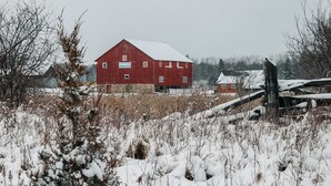 A red barn with a sign that reads 'Baker Creek Children's Farm' in a snowy field.