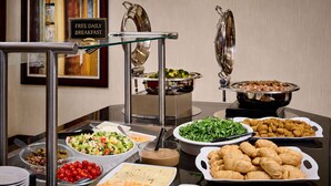 A buffet with various food items including salads, bread, and pastries.