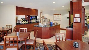 A hotel lobby with a reception desk, seating area, and a kitchenette.