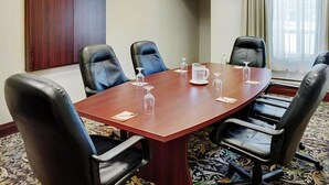 A conference room with a wooden table, black leather chairs, and a whiteboard.