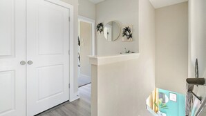 A hallway with a white door, a mirror, and wall-mounted decorations. - 3BR Gated Community Houston Home  + Parking (Houston)