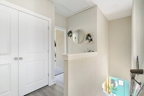 A hallway with a white door, a mirror, and wall-mounted decorations. - 3BR Gated Community Houston Home  + Parking (Houston)