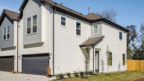 A two-story residential building with a garage, a front porch, and a small front yard. - 3BR Gated Community Houston Home  + Parking (Houston)