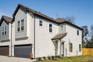 A two-story residential building with a garage, a front porch, and a small front yard. - 3BR Gated Community Houston Home  + Parking (Houston)