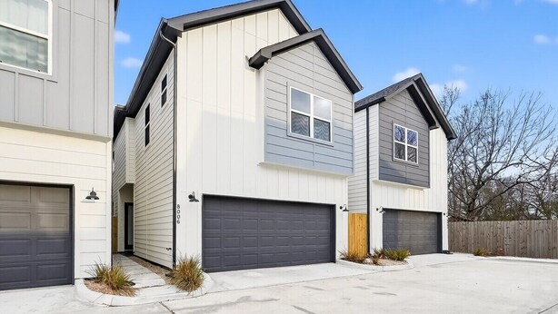 A residential building with a garage, a driveway, and a wooden fence. - Designer 3BR w/ Fireplace, Yard & Free Parking (Houston)