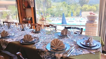 Une table à manger dressée pour un repas, avec vue sur une piscine et des montagnes.