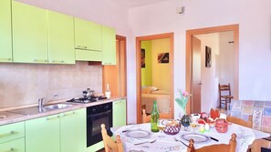 A kitchen with green cabinets, a dining table set with plates, glasses, and a bottle.