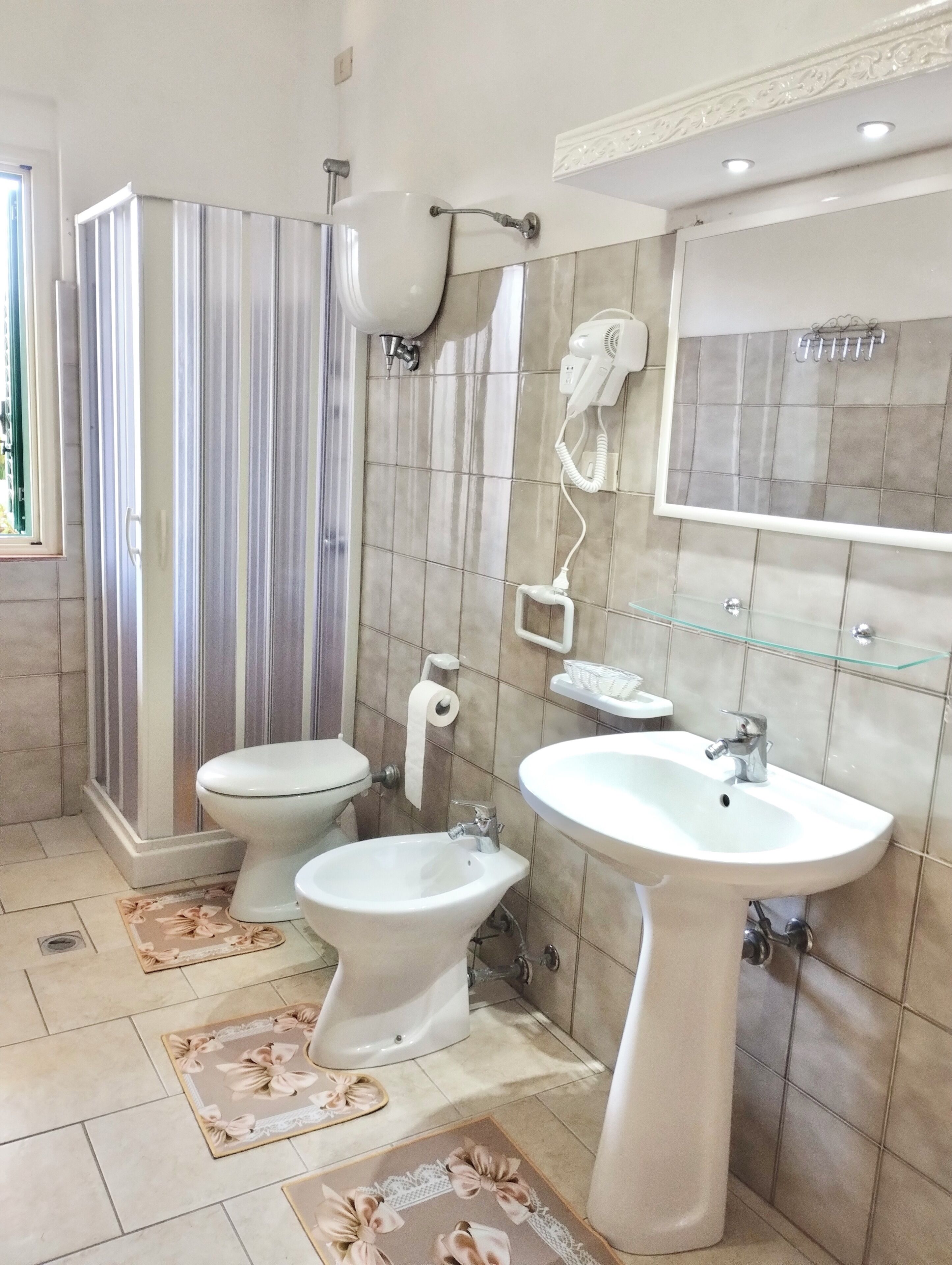A bathroom with a toilet, bidet, sink, and a shower area.