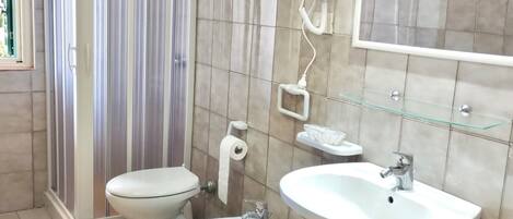 A bathroom with a toilet, bidet, sink, and a shower area.