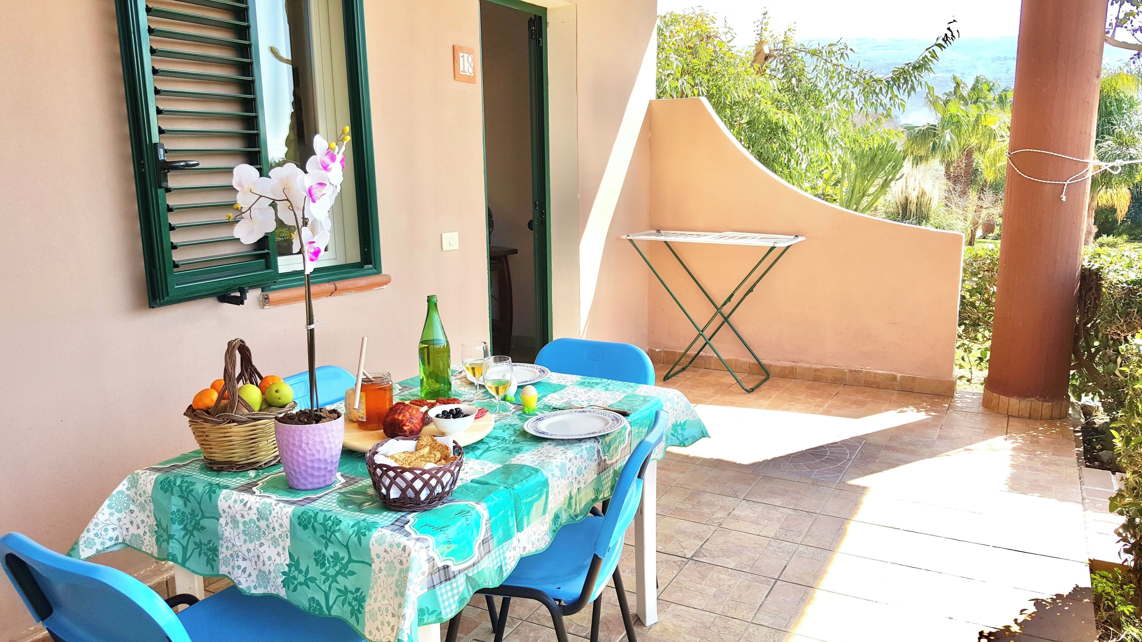 Une table à manger installée à l’extérieur, avec vue sur la mer, une fenêtre avec des volets et une table pliante.