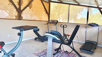Une salle de sport équipée de divers appareils, notamment un tapis de course, un vélo elliptique et un vélo d’appartement.