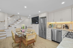 A modern kitchen with stainless steel appliances, a dining area with a glass table, and a staircase with wooden steps. - North End Entire House / Heart of Boston (Boston)