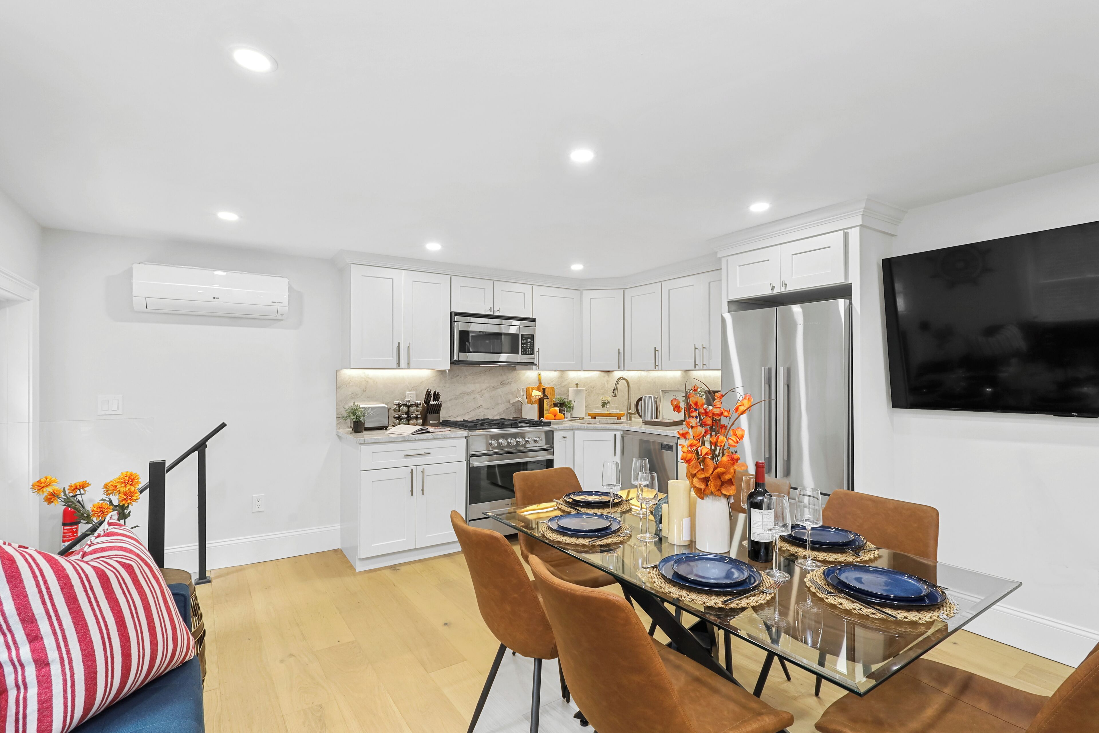 A modern kitchen with white cabinets, a stainless steel refrigerator, and a microwave.