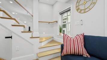 Et moderne interiør med trappe, en blå sofa og et stort vægur.