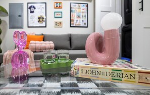 A glass table with a pink spherical object, a green container, and a book titled 'JOHN DERIAN' with a puzzle box. - North End Entire House / Heart of Boston (Boston)