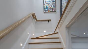 Eine Treppe mit Holzstufen und Geländer, die zu einer Empore mit einem an der Wand befestigten Kunstwerk führt.