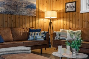 Ett mysigt rum med två bruna soffor i läder, en golvlampa och en inramad tavla på väggen.