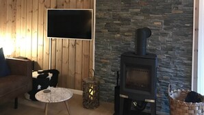 Een gezellige woonkamer met een stenen openhaard, een op de muur bevestigd hertengestaltebeeld en een comfortabele zithoek met een flatscreen televisie.