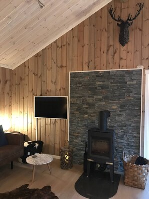 A cozy living room with a stone fireplace, a mounted deer head, a flat-screen TV, and a comfortable seating area. - The Cozy Family Mountain Retreat (Nybergsund)