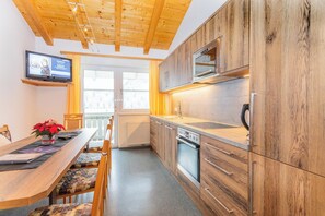 Eine moderne Küche mit Holzausstattung, einem Einbauofen und einer Mikrowelle.