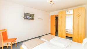 A bedroom with a bed, a chair, a wardrobe, and a picture on the wall. - Gruber's Gästehaus - Ferienwohnungen (Viehhofen)