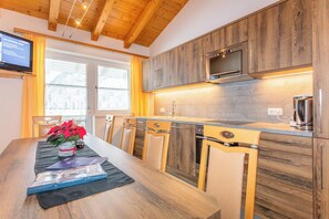 Eine moderne Küche mit Holzschränken, einer eingebauten Mikrowelle und einem Essbereich mit Tisch und Stühlen.