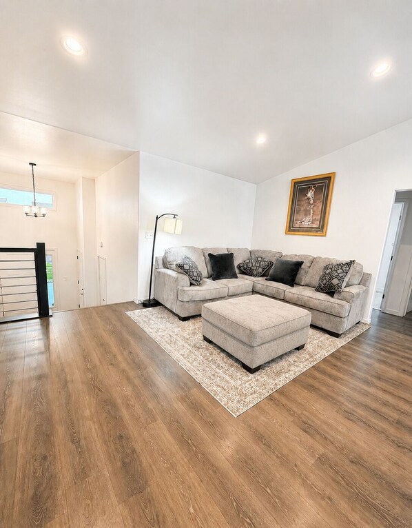 A modern living room with a sectional sofa, ottoman, patterned rug, and a floor lamp.