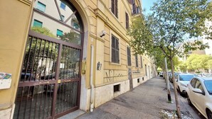 A yellow building with a large arched window and a metal gate. - Amiterno Elegance - by Domus & Dimore (Rome)