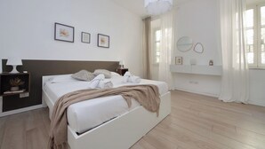 A modern bedroom with a large bed, bedside tables, a hanging light fixture, and artwork on the wall. - Amiterno Elegance - by Domus & Dimore (Rome)