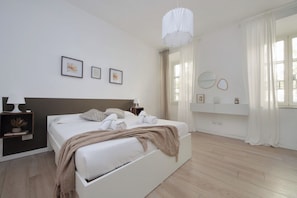 Ein modernes Schlafzimmer mit einem großen Bett, Nachttischen, einer Hängelampe und Kunstwerken an der Wand.