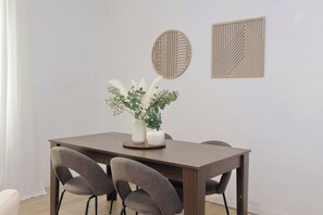 Een eettafel met twee stoelen, een vaas met witte bloemen en twee kunstwerken aan de muur.
