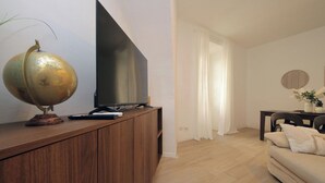 A living room with a wooden entertainment unit, a flat-screen TV, a globe, and a sofa. - Amiterno Elegance - by Domus & Dimore (Rome)