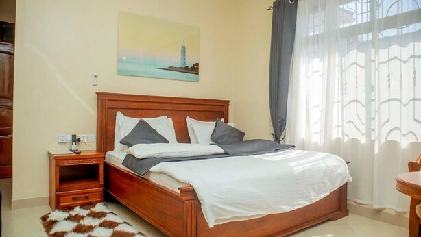 Un dormitorio con una cama de madera, una mesita de noche, una alfombra y un cuadro en la pared.