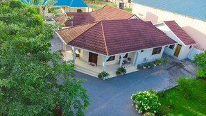 A residential building with a red-tiled roof, a covered porch, and a paved driveway.