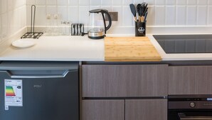 Et køkken med opvaskemaskine, kaffemaskine og et knivdisplay på bordpladen.