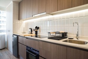 A modern kitchen with wooden cabinets, a stainless steel sink, and a built-in oven. - Marchant P Apartments by Andes (Ñuñoa)