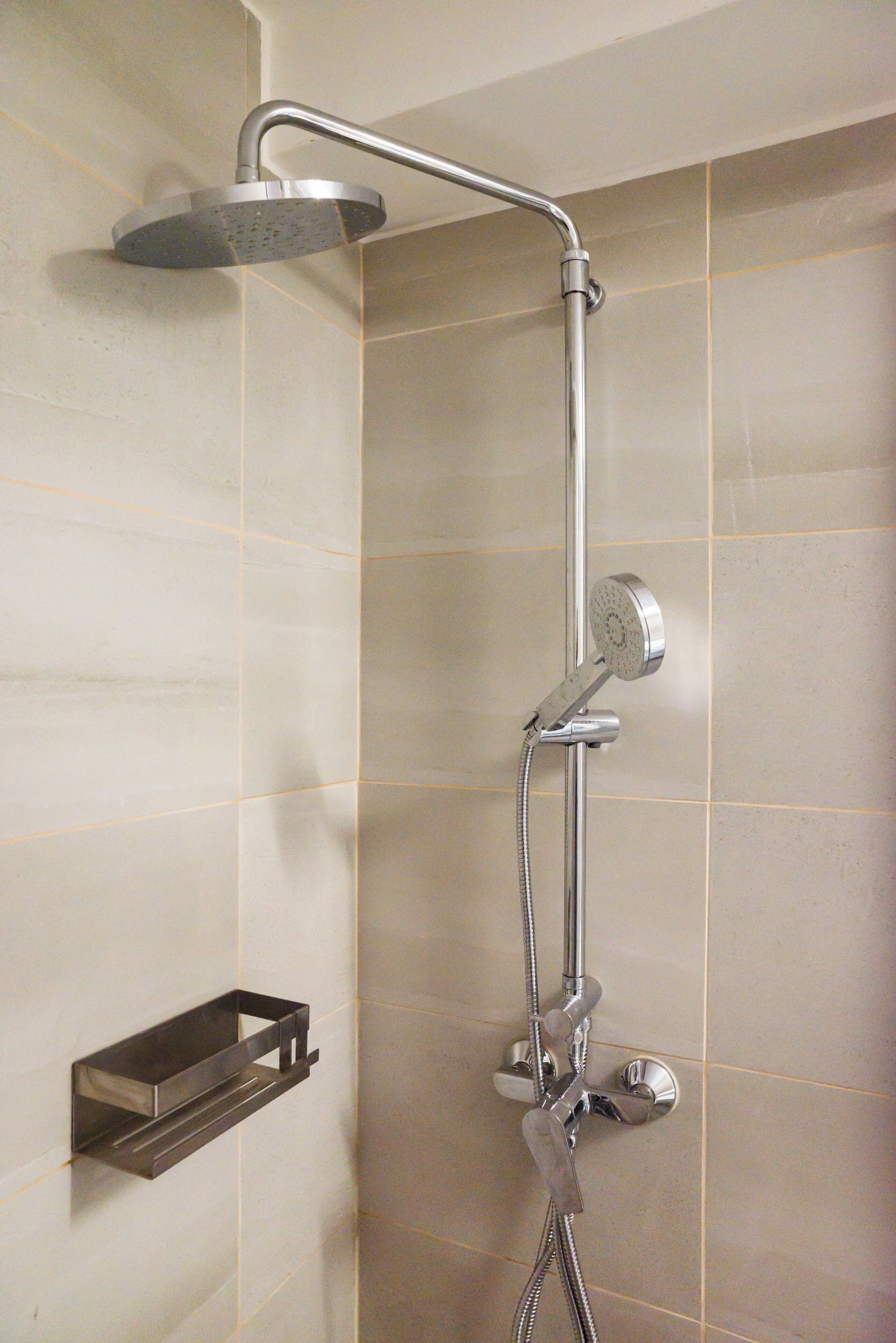 Ducha con cabezal de ducha de mano, grifo empotrado y manguera de mano.