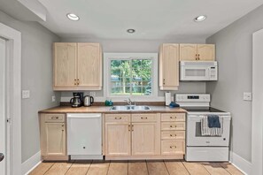 Una cocina compacta con armarios de madera, lavavajillas integrado, microondas y estufa.