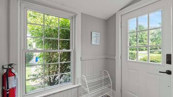 A room with two large windows, a white door, and a fire extinguisher mounted on the wall.