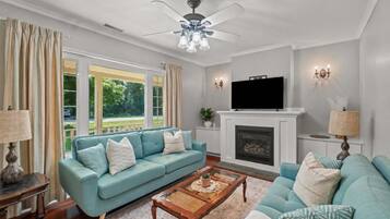 A living room with a sofa, a coffee table, a fireplace, and a television.